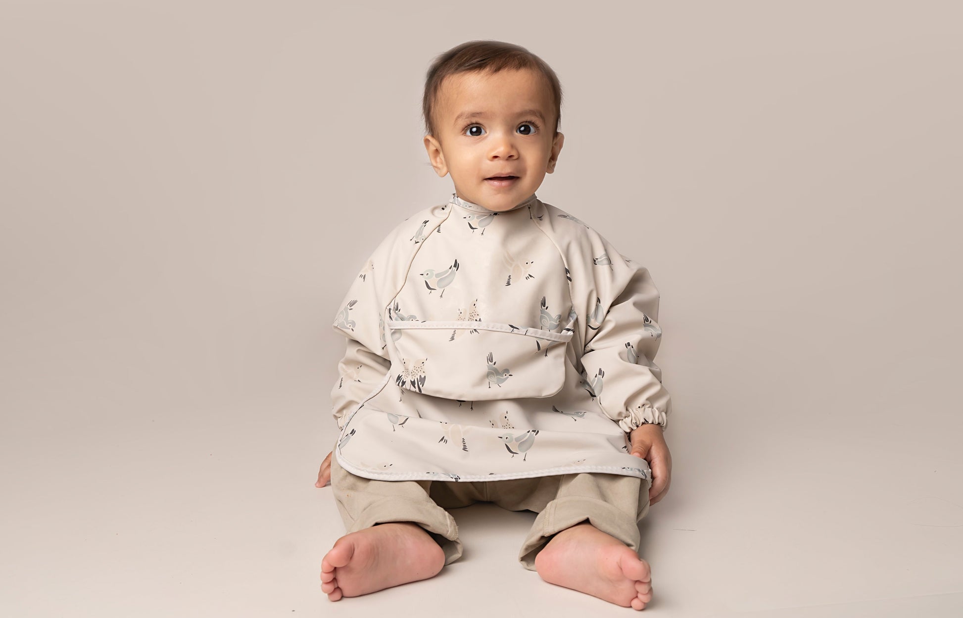  A practical long sleeve weaning bib with elasticated cuffs, designed to handle messes from food, paint, and playtime fun. The bib features a catch-all pocket to prevent spills and splatters, along with a double-button neck fastening for a secure fit and easy dressing. It's waterproof and machine washable for quick cleanup.